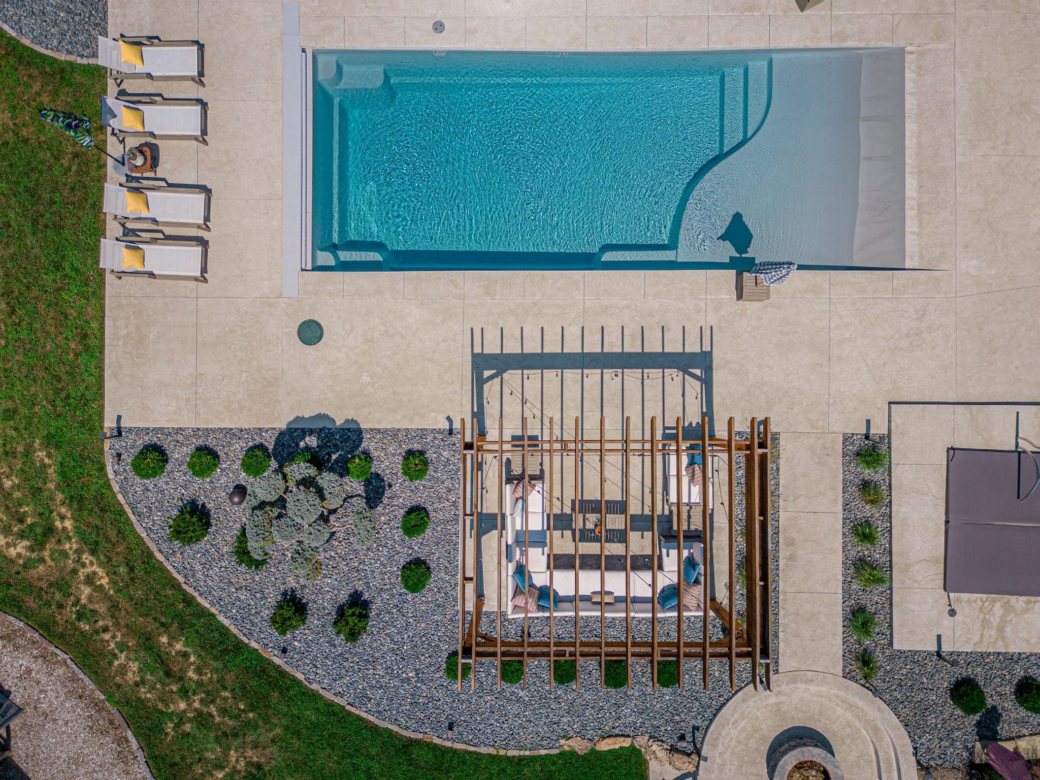 Aerial view of a fiberglass pool installation with paver patio and pergola