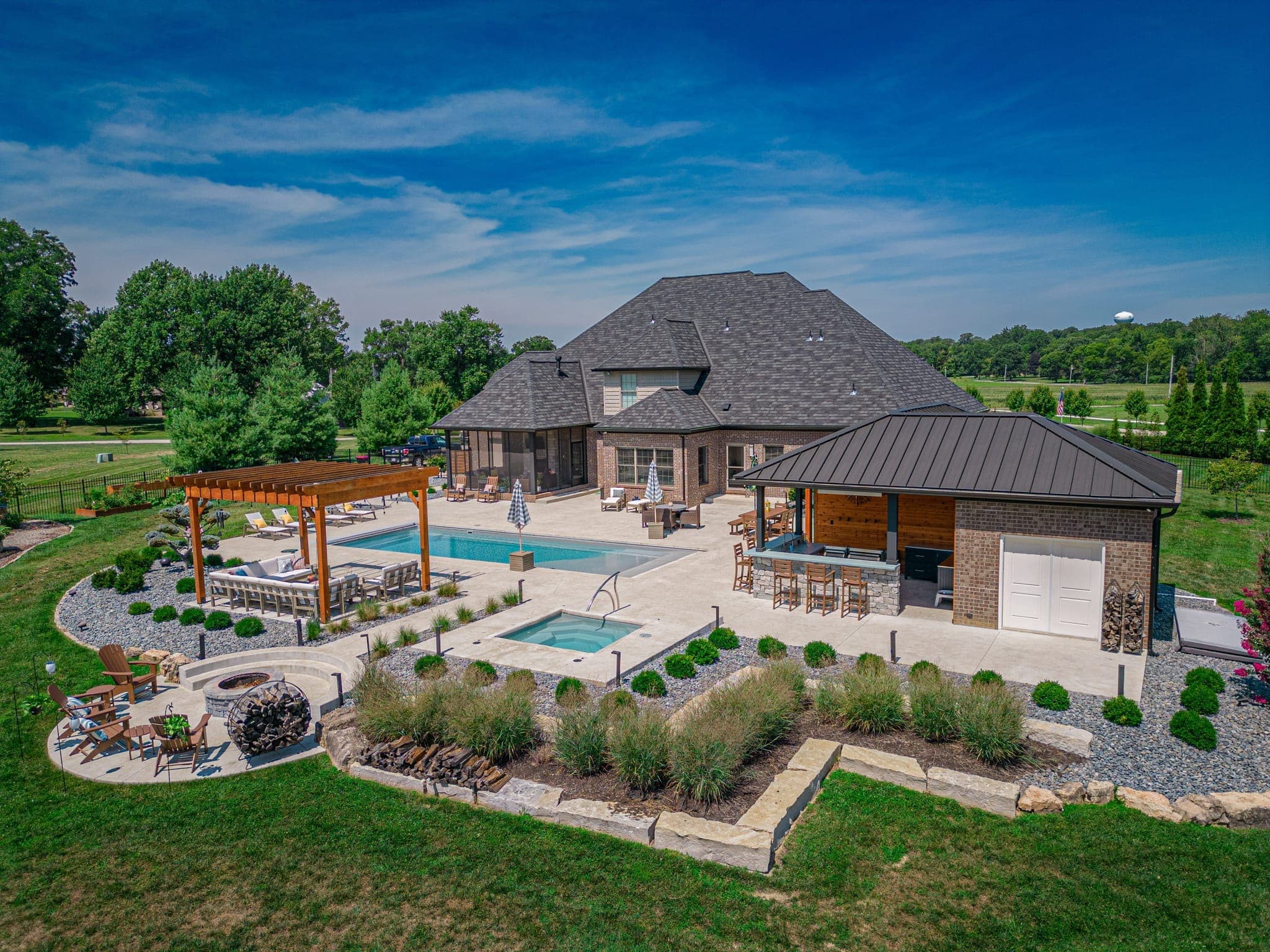 Lush residential landscape with stone patio, mature plantings, and outdoor living space