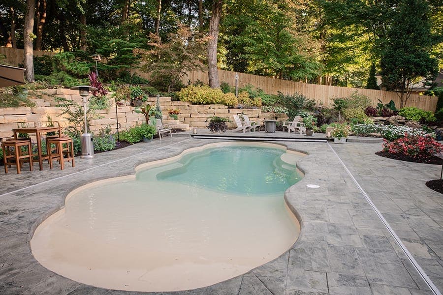 Fiberglass pool with paver patio and lush landscape plantings