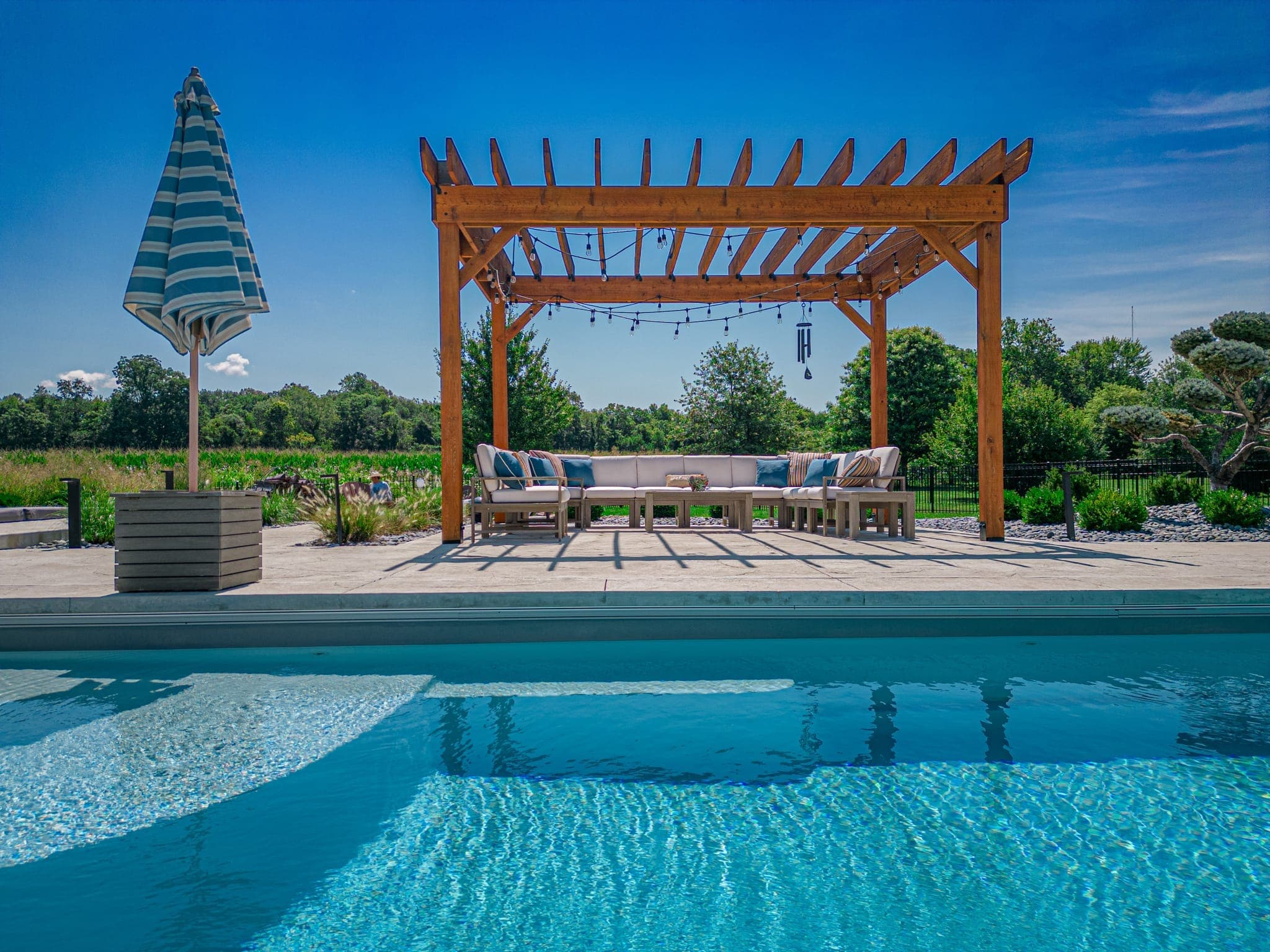 A beautifully landscaped pool with a custom pergola at golden hour